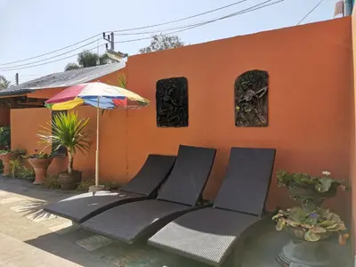 a group of chairs and an umbrella in front of a house at Serene Villa Phuket in Chalong