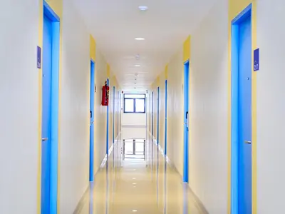 an empty corridor of a hospital hallway with blue and yellow doors at HOP INN Phuket Old Town in Phuket Town