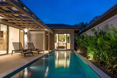 an indoor swimming pool with two chairs and a house at Boutique 2BR Pool Villa Dalaa 1, Gated Residence, Kamala Beach in Kamala Beach