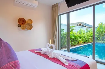 a bedroom with a bed with a view of a pool at Boutique Resort 2BR Pool Villa Dalaa 2, Kamala Beach in Kamala Beach