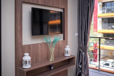a television on a wall with a vase on a shelf at NARA Condo 1BR Pool View NBC Nai Harn in Nai Harn Beach