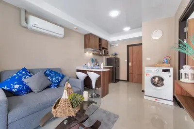 a living room with a gray couch and a kitchen at NARA Condo 1BR Pool View NBC Nai Harn in Nai Harn Beach