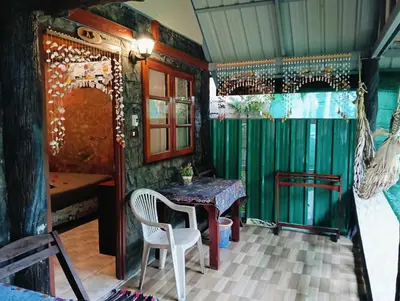 a table and chair in a room with green walls at P P Garden Home Bungalow in Phi Phi Don