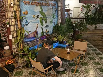 a man sitting at a table in front of a mural at P P Garden Home Bungalow in Phi Phi Don