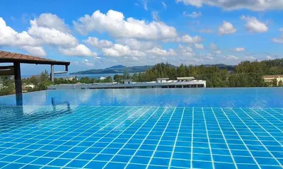 a large blue swimming pool with a view of the water at Aristo Resort Surin Beach K02 in Surin Beach