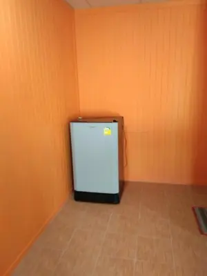 a small white refrigerator in a room with orange walls at Baan Kebsap บ้านเก็บทรัพย์ in Ko Yao Noi