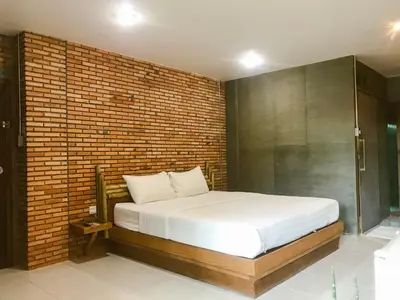 a bed in a room with a brick wall at Cafe'@luv22 in Phuket Town