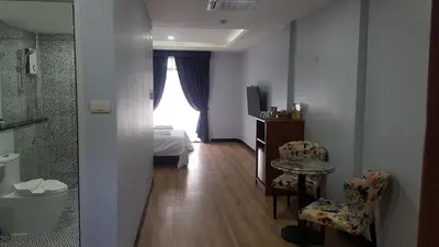 a room with a bedroom with a bed and a table and chairs at La Capannina Hotel Patong in Patong Beach