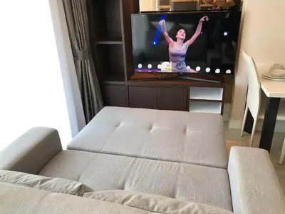 a living room with a couch in front of a tv at Aristo Resort Surin Beach J16 in Phuket Town