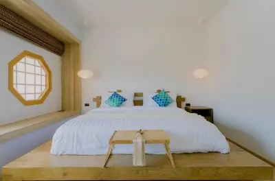 a bedroom with a white bed and a wooden table at Wayla Villa@Maikhaobeach in Mai Khao Beach
