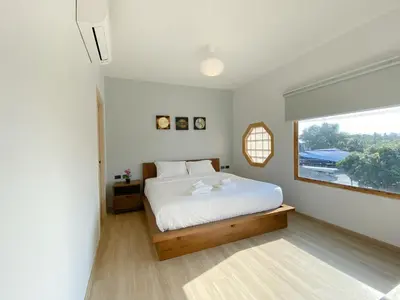 a white bedroom with a bed and a window at Wayla Villa@Maikhaobeach in Mai Khao Beach