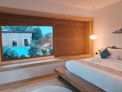 a bedroom with a large window with a view of a yard at Wayla Villa@Maikhaobeach in Mai Khao Beach
