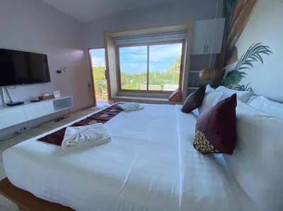 a large white bed in a room with a window at Wayla Villa@Maikhaobeach in Mai Khao Beach