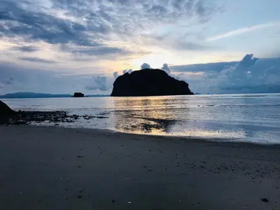 a beach with a large rock in the water at Relaxing House Koh Yao Yai in Ko Yao Yai