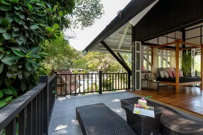 a porch of a house with a table and chairs at Patong Garden House - Luxury Villa in Patong Hills in Patong Beach