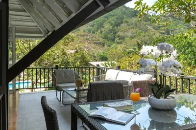 a patio with a table and chairs on a balcony at Patong Garden House - Luxury Villa in Patong Hills in Patong Beach