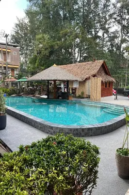 a large blue swimming pool with a gazebo at Ginis Beach Resort in Kamala Beach