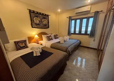 two beds in a hotel room with towels on them at Ginis Beach Resort in Kamala Beach