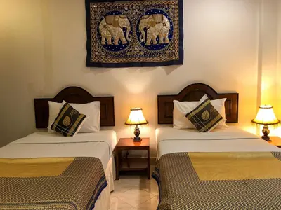 two beds in a hotel room with two lamps at Ginis Beach Resort in Kamala Beach