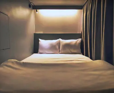 a bed with white sheets and pillows in a room at Capzule Bed Phuket in Phuket Town