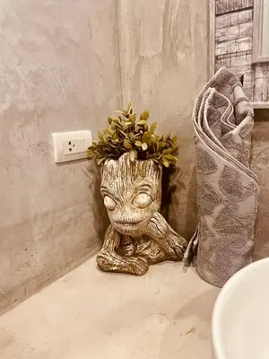 a statue of a baby groot sitting next to a lightswitch at Destination39 in Thalang