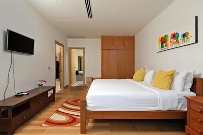 a bedroom with a white bed and a television at Suite Cascade 2BR Family Deluxe Kamala Falls in Kamala Beach