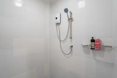 a shower in a white bathroom with a shower head at Bangla house with 4 houses Pick house before BOOK in Patong Beach