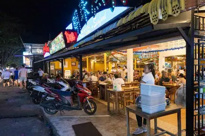a group of people sitting outside a restaurant at night at Sara's Nest - Top Floor Seaview apartments in Nai Harn Beach