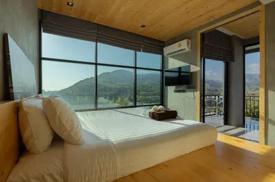 a bedroom with a large bed with a large window at Sara's Nest - Top Floor Seaview apartments in Nai Harn Beach