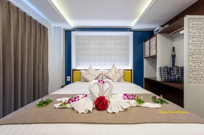 a bedroom with a bed with two people dressed in white at Sino Siam Hotel in Klong Muang Beach