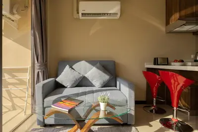 a living room with a chair and a glass table at NaiHarn Sea Condo by Holy Cow, 1-BR, mountain view in Nai Harn Beach