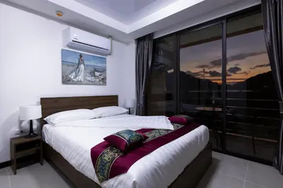 a bedroom with a bed and a large window at NaiHarn Sea Condo by Holy Cow, 1-BR, mountain view in Nai Harn Beach