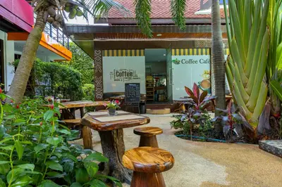 a store with a table and stools in a garden at NaiHarn Sea Condo by Holy Cow, 1-BR, mountain view in Nai Harn Beach