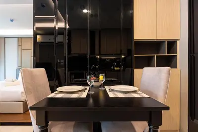 a black dining room table with chairs and a kitchen at Panora Surin by Holy Cow, 1-BR, courtyard view in Surin Beach