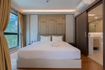 a bedroom with a large white bed with two towels at Panora Surin by Holy Cow, 1-BR, courtyard view in Surin Beach