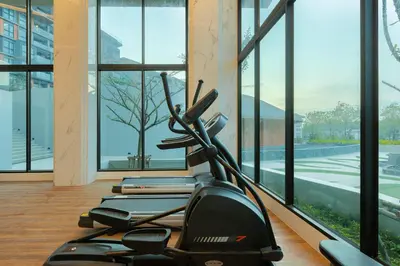 a gym with a treadmill and large windows at Panora Surin by Holy Cow, 1-BR, courtyard view in Surin Beach