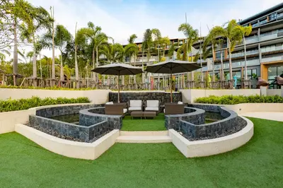 an outdoor patio with chairs and umbrellas and grass at Panora Surin by Holy Cow, 1-BR, courtyard view in Surin Beach