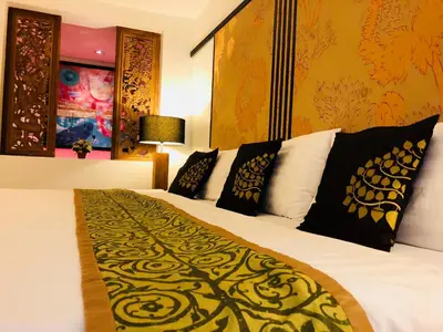 a hotel room with a bed with white sheets and black pillows at Baipho Lifestyle in Patong Beach