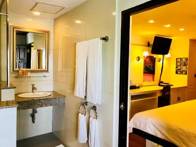 a bathroom with a sink and a bed and a mirror at Baipho Lifestyle in Patong Beach