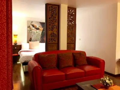 a living room with a red couch and a bed at Baipho Lifestyle in Patong Beach