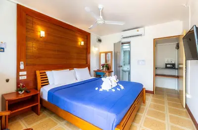 a bedroom with a blue bed with a wooden headboard at The Expat Hotel Patong in Patong Beach
