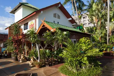 a building with trees and plants in front of it at The Expat Hotel Patong in Patong Beach