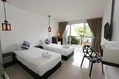 a hotel room with two beds and a chair at The Nest Resort Patong in Patong Beach
