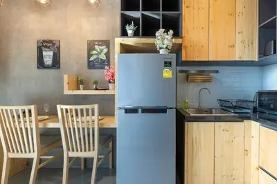 a kitchen with a refrigerator and a table with chairs at Relife Windy by Holy Cow, courtyard view in Nai Harn Beach