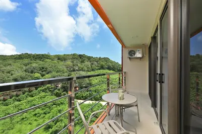 a balcony with a table and chairs and a view at NaiHarn Sea Condo, Top floor, Mountain View in Nai Harn Beach