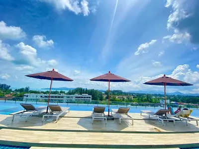 a group of chairs and umbrellas next to a pool at Aristo Resort Surin Beach K5 in Phuket Town
