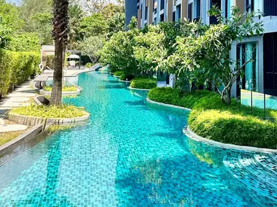 a swimming pool with blue water in front of a building at Aristo Resort Surin Beach K5 in Phuket Town