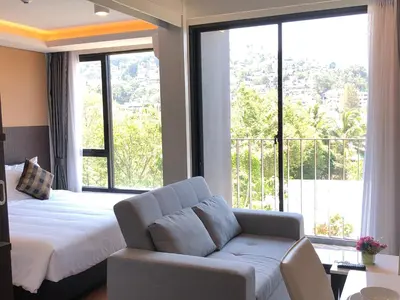 a bedroom with a bed and a couch and a large window at Aristo Resort Surin Beach K5 in Phuket Town