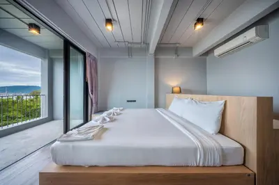 a bedroom with a large bed and a large window at SHIN Arch39 Phuket Beach Front - SHA Plus in Chalong