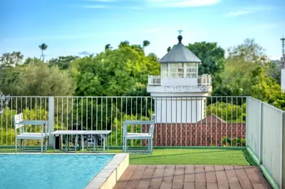 a swimming pool with two chairs and a lighthouse at SHIN Arch39 Phuket Beach Front - SHA Plus in Chalong